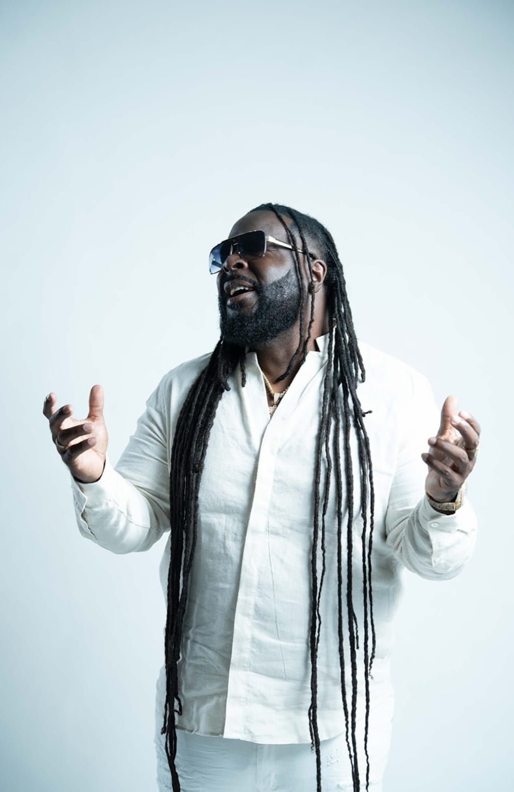 Monty G performing in all white, arms open